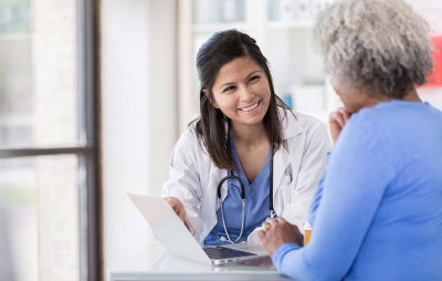 Medical professional and patient smiling while reviewing laptop