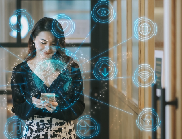 Woman standing with phone surrounded by blue digital icons